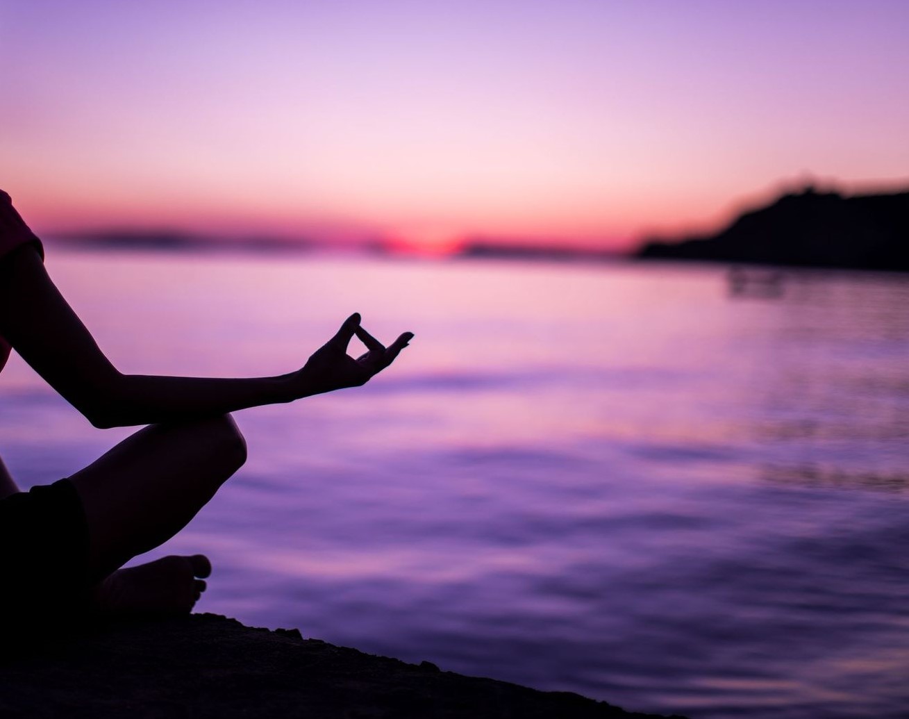 person meditating by water